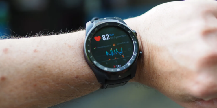 Close-up of a smartwatch showing heart rate and data on a person's wrist outdoors.
