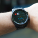 Close-up of a smartwatch showing heart rate and data on a person's wrist outdoors.