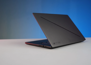 Elegant black laptop on a minimalist desk with a gradient blue background, perfect for tech and work concepts.