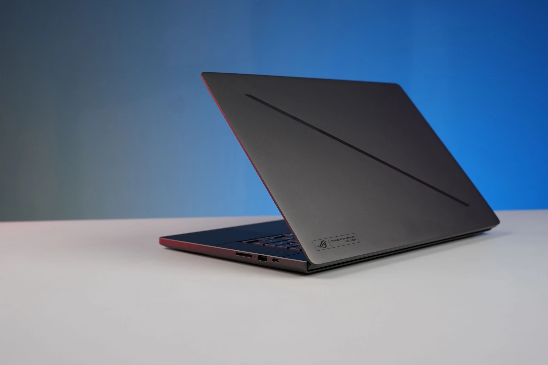 Elegant black laptop on a minimalist desk with a gradient blue background, perfect for tech and work concepts.