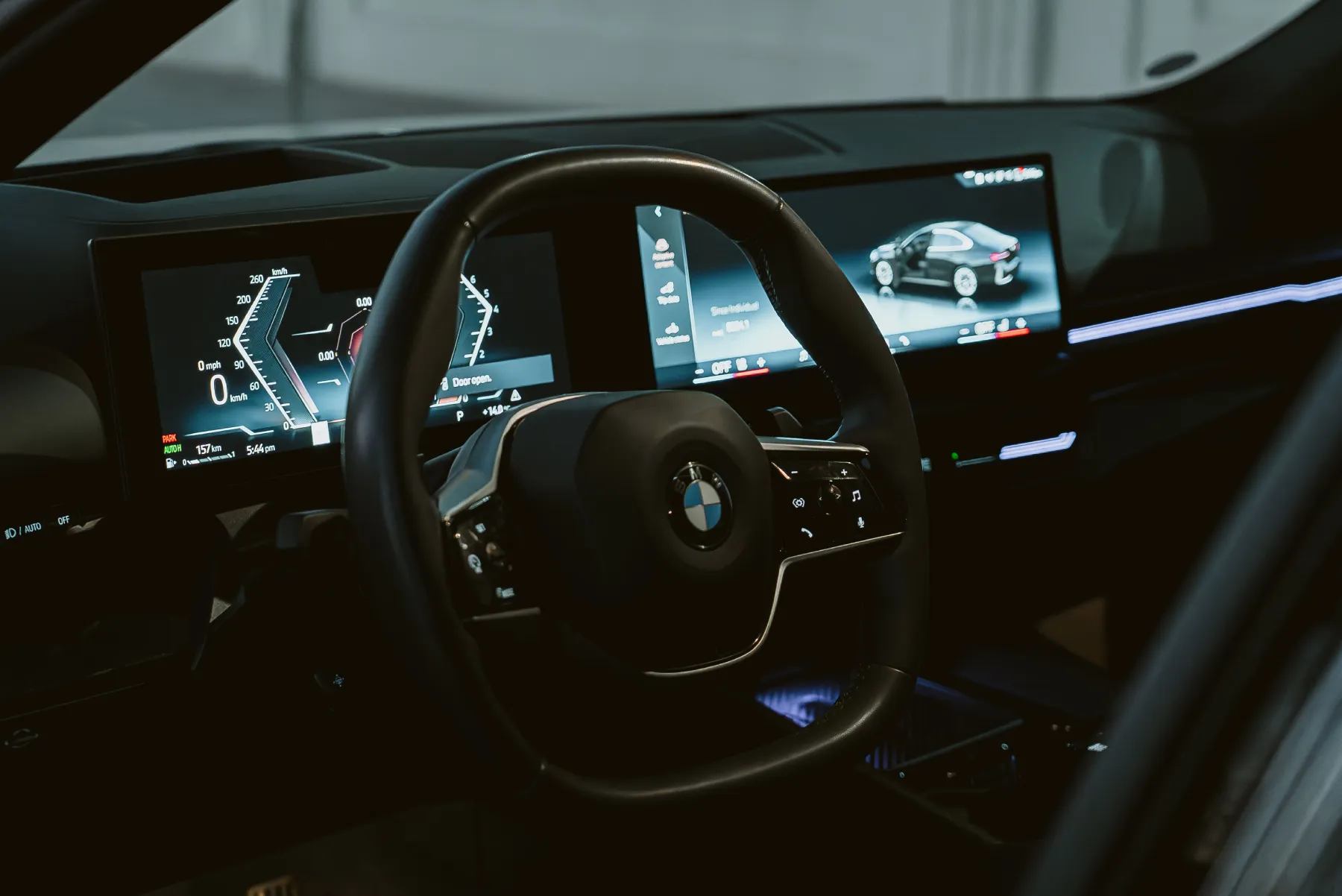 Close-up view of a BMW interior featuring a steering wheel and modern dashboard screens in Erbil