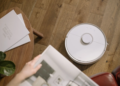 A sleek robot vacuum cleaner operating on a wooden floor, symbolizing modern home technology