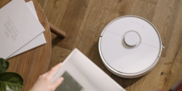 A sleek robot vacuum cleaner operating on a wooden floor, symbolizing modern home technology