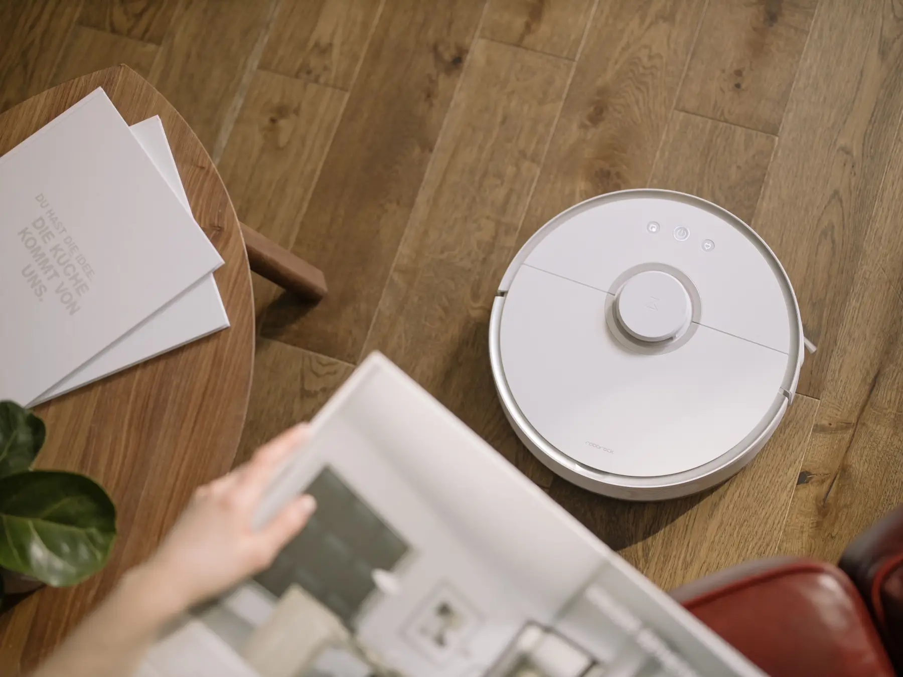 A sleek robot vacuum cleaner operating on a wooden floor, symbolizing modern home technology