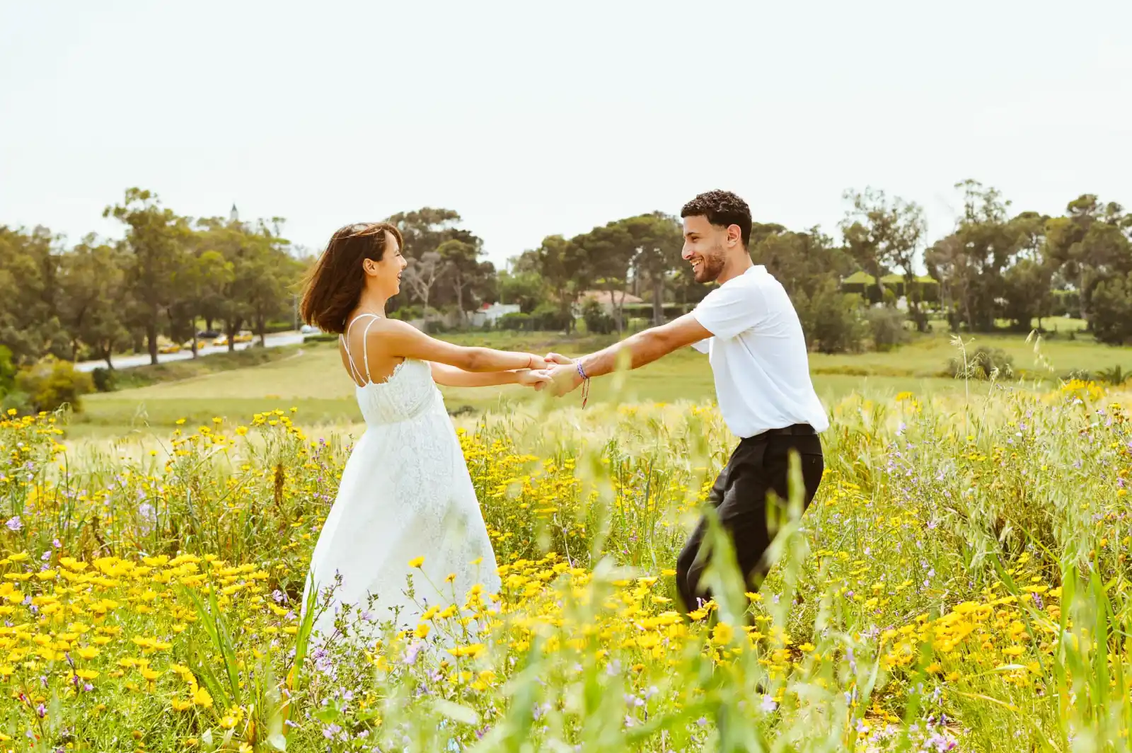 A happy couple dances in a sunny flower-filled meadow, embracing nature and love.