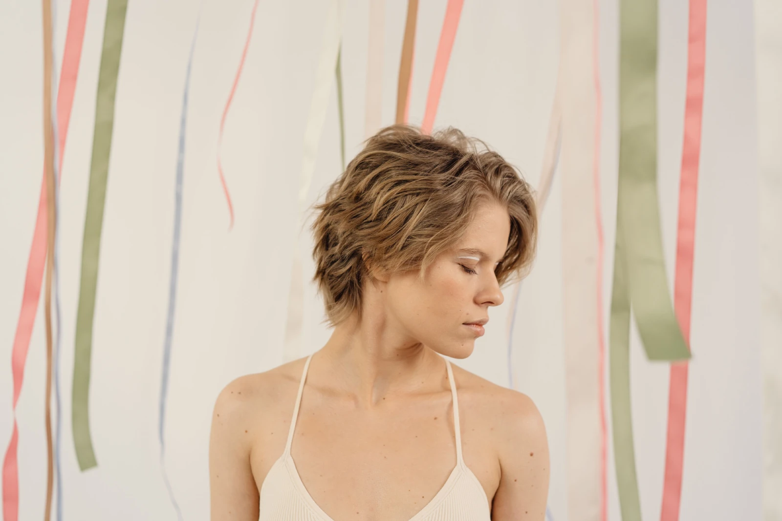 Beautiful portrait of a woman with short hair and closed eyes, set against a backdrop of colorful ribbons