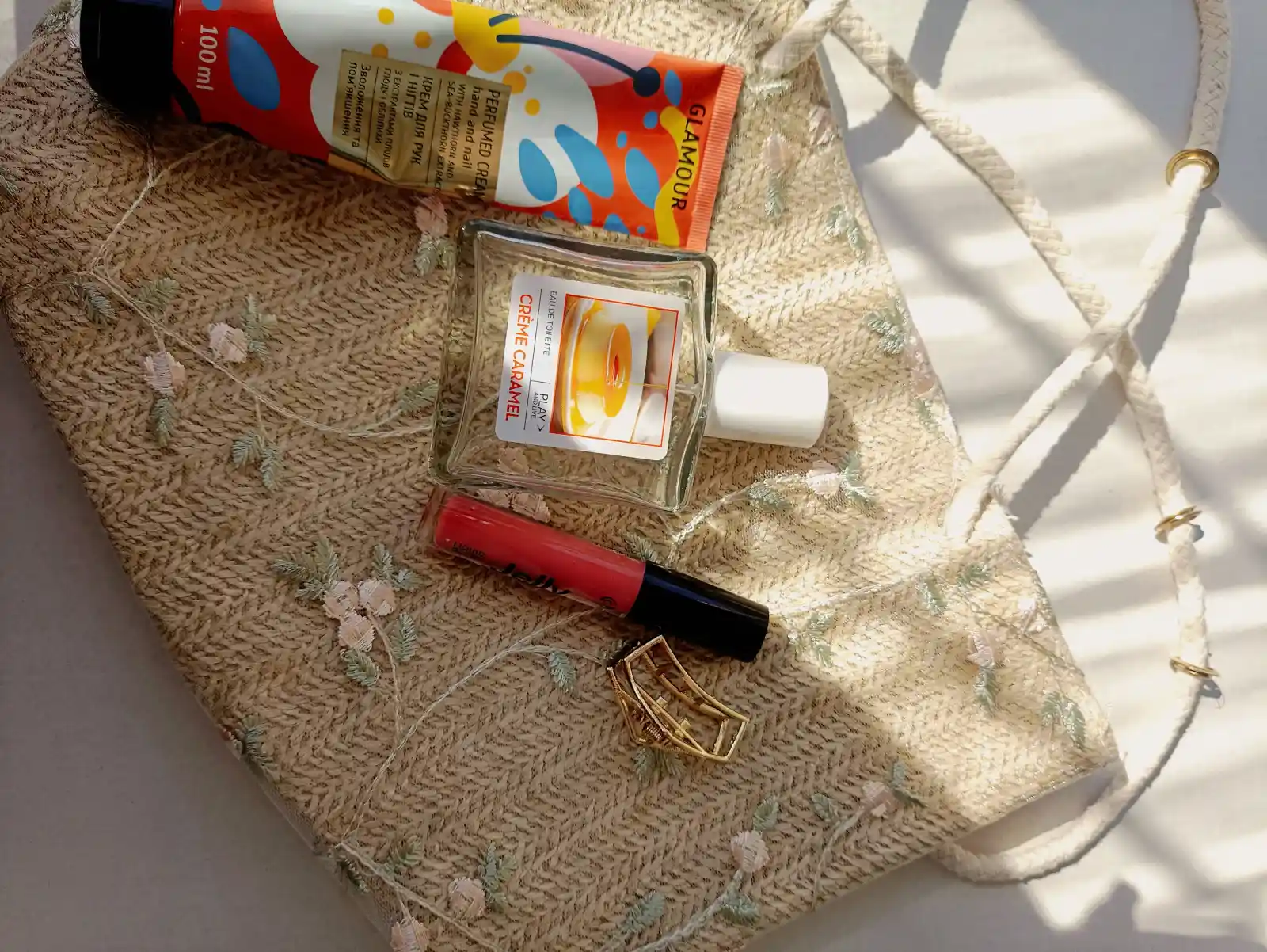 Stylish flat lay of cosmetic products on an embroidered bag in soft sunlight