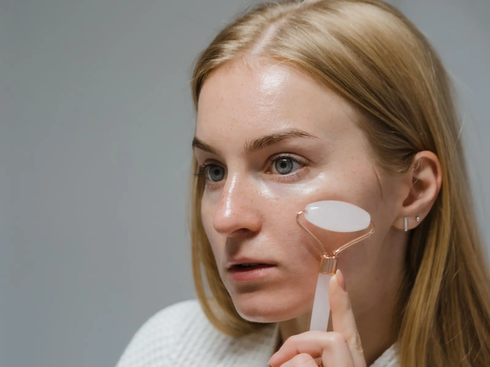 Close-up of a woman using a jade roller for her skincare routine, focusing on fresh skin and beauty care