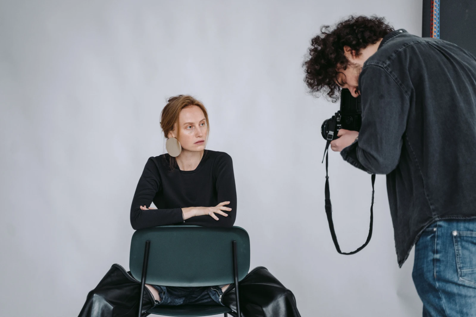 Female model posing in a stylish studio photoshoot with photographer capturing the moment.