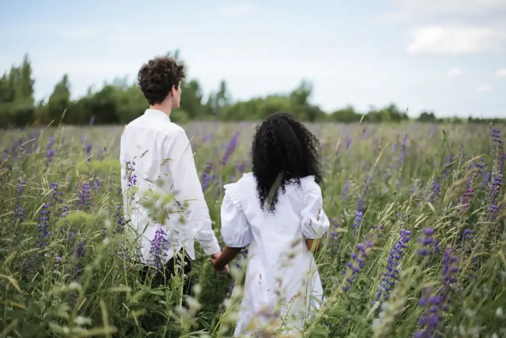 A couple walking hand in hand through a lush lupine field, capturing love and nature.