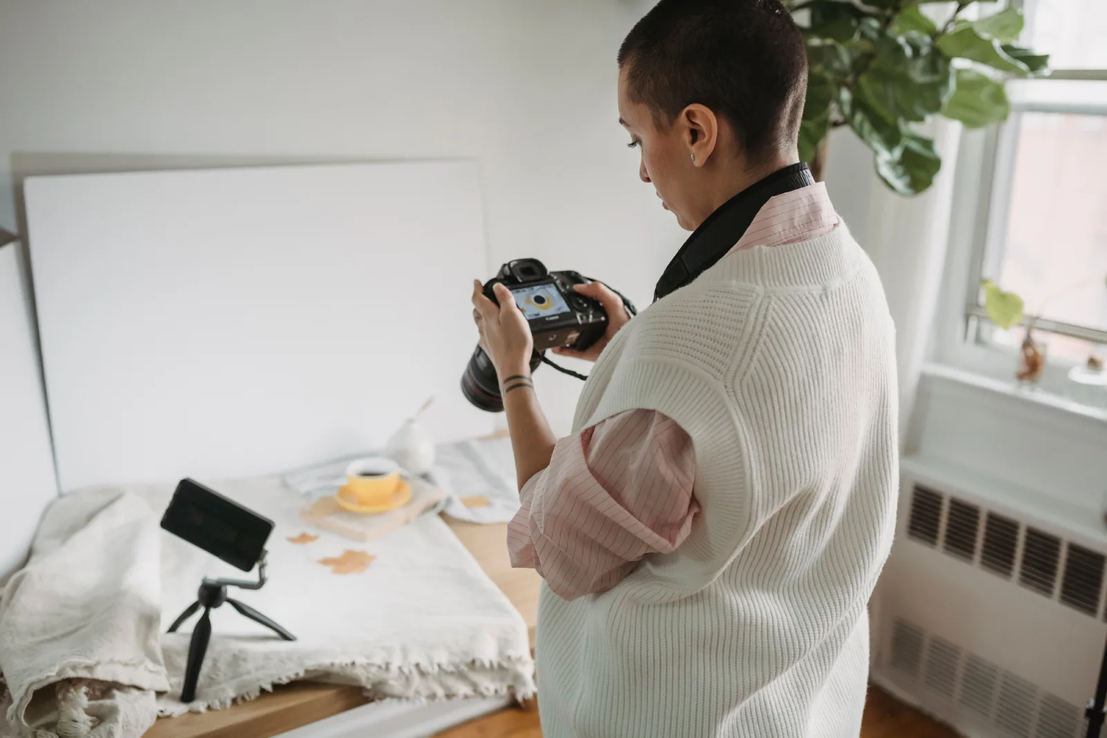 A woman photographer prepares her equipment for an indoor shoot with natural lighting.