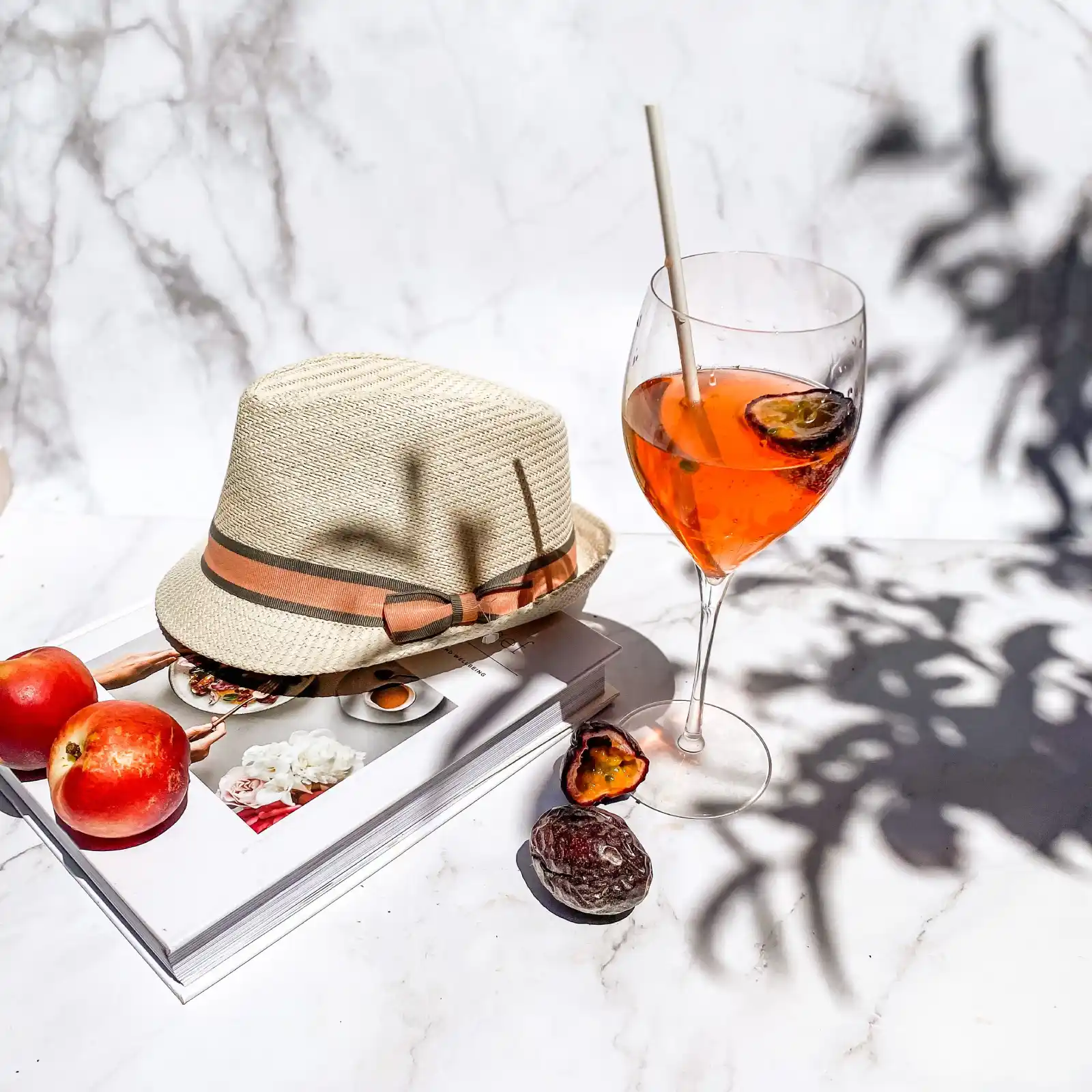 Elegant Aperol drink with hat and fruits casting shadows, evoking summer vibes.