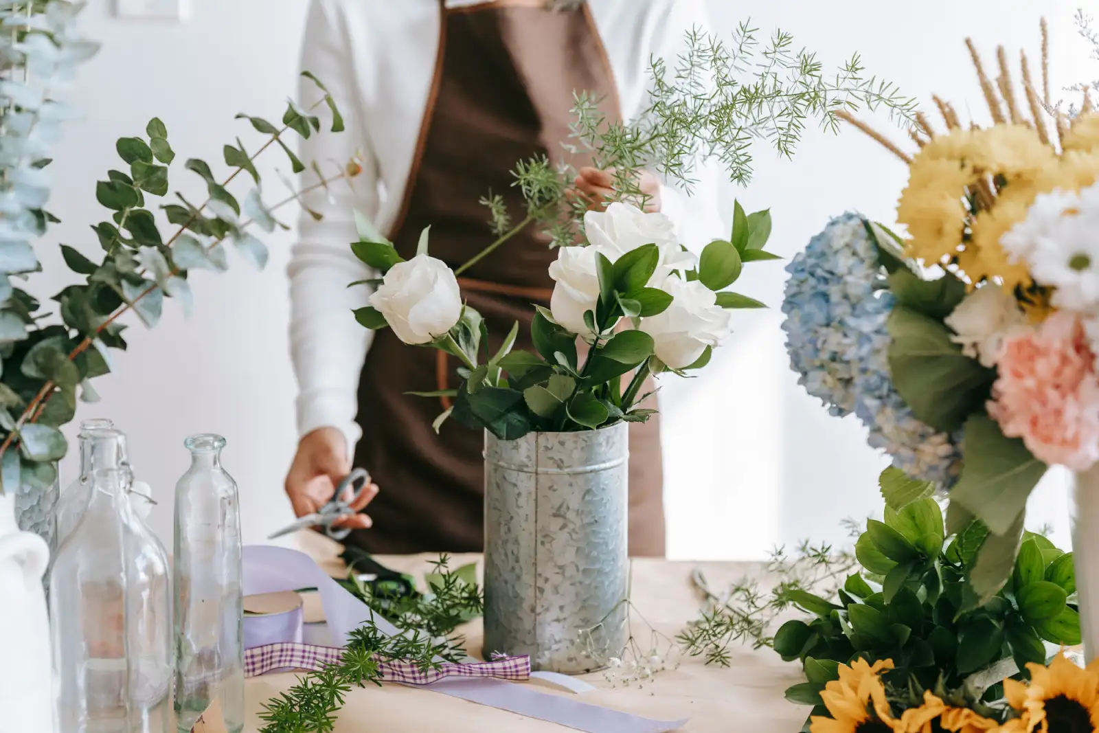 Florist arranges a colorful bouquet in a bright indoor workspace, showcasing floral artistry.